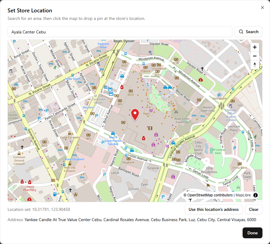 The Set Store Location dialog: a search box with the queried area, a map with a red pin dropped on the store's spot, the pin's coordinates, a Use this location's address button, and the resolved address shown below the map